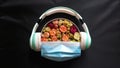 Gift box with colorful roses, headphones, a medical mask isolated on a black background.