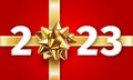 2023 Gift Box Decoration. Happy New Year Greeting Card with a gold ribbon gift bow and the number 2023 on a red background. New Royalty Free Stock Photo