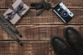 Gift box for father`s day with men`s accessories bow-tie, retro camera, suspenders and leather shoes on a wooden background.