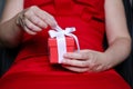 Gift box in female hands, woman in red evening dress holding the present Royalty Free Stock Photo