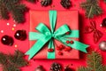 Gift box and fir branches with Christmas decoration on red background, flat lay Royalty Free Stock Photo