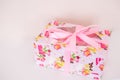 Gift box with flower pattern and pink ribbon on white background Royalty Free Stock Photo
