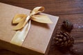 Gift box with gold bow and cone spruce on wood background Royalty Free Stock Photo