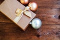 Gift box with gold bow with hristmas balls on wood background