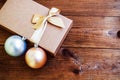 Gift box with gold bow with hristmas balls on wood background