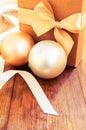 Gift box with gold bow with hristmas balls on wood background