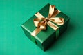 Gift box with golden satin ribbon and bow on green background. Generative AI Royalty Free Stock Photo