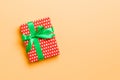 Gift box with green bow for Christmas or New Year day on orange background, top view with copy space Royalty Free Stock Photo