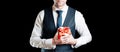 Gift box hand. Happy young business man holding surprise giftbox present with red ribbon isolated on black background Royalty Free Stock Photo