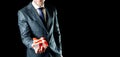 Gift box hand. Happy young business man holding surprise giftbox present with red ribbon  on black background Royalty Free Stock Photo