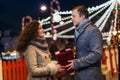 Gift box in the hands of a man and a woman against the background of Christmas street lights. Romantic date Loving couple on Royalty Free Stock Photo