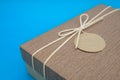 A gift box isolated over blue background with copy space. Box is tied with a cord with a label with Wishes and Happiness. Holiday