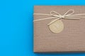 A gift box isolated over blue background with copy space. Box is tied with a cord with a label with Wishes and Happiness. Holiday
