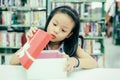 Gift box for kids girl. White box with red bow in the smiling asian girl hands for give a gift in the library, happy and surprise Royalty Free Stock Photo