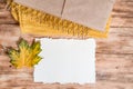 Gift box.kraft packaging.Mockup torn paper for your notes. Autumn bright dry leaves.Yellow knitted sweater.wooden background.flat Royalty Free Stock Photo