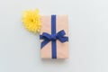 Gift box with kraft paper, a blue ribbon and a yellow flower on a light blue background. Flat lay for father`s day concept Royalty Free Stock Photo