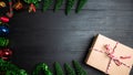 A gift box made of brown paper, tied with a red white bowstring, placed on a wooden board decorated with Christmas trees and Royalty Free Stock Photo