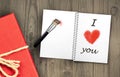 Gift box and message I love you in written in notebook and red heart shape painted with makeup paintbrush as message celebrating