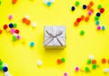 Gift box with multi-colored confetti on a yellow background. Happy birthday concept. Royalty Free Stock Photo