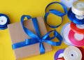 Gift box packaging on a yellow background. A lot of bright satin ribbons Royalty Free Stock Photo