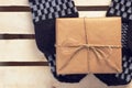 Gift box packed brown paper and twine on handmade mittens lying on wooden grid panel top view vintage styled