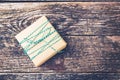 Gift box packed in kraft paper with a green white rope. Gift on rustic wooden background, copy space. Holiday present in vintage s