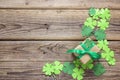 Gift box with paper clover leaves on the old wooden background. Royalty Free Stock Photo