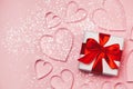 Gift box and paper hearts with sparkling glitter on pink background. Romantic st. Valentine`s day concept of greetings. Top view,