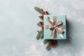Gift box in pastel green color with silver ribbon and fir branch with berry on light green background, Christmas background. Royalty Free Stock Photo
