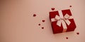 A gift box with a pink ribbon on a red box with hearts scattered around it. 3d