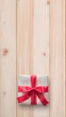 Gift box present isolated with clipping path with red bow satin ribbon over brown wrapping paper on white pine wood background Royalty Free Stock Photo