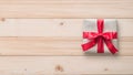 Gift box present isolated with clipping path with red bow satin ribbon over brown wrapping paper on white pine wood background f Royalty Free Stock Photo