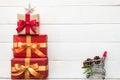 Gift box present stack in Christmas tree shape with red-gold ribbon, star, spruce twig, pine cone and shopping trolley on white Royalty Free Stock Photo