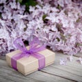 Gift box with purple bow and lilac on wood Royalty Free Stock Photo