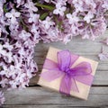 Gift box with purple bow and lilac on wood Royalty Free Stock Photo