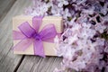 Gift box with purple bow and lilac on wood Royalty Free Stock Photo