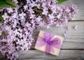 Gift box with purple bow and lilac on wood Royalty Free Stock Photo