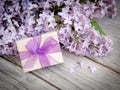 Gift box with purple bow and lilac on wood Royalty Free Stock Photo