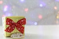 Gift box with red bow and defocused christmas lights on the background. With snow effect Royalty Free Stock Photo