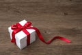 Gift box with red bow on rustic table, christmas or another celebration