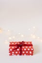 Gift box in red paper packaging with white polka dots, tied with a red satin ribbon with a bow and a glass heart on a white Royalty Free Stock Photo