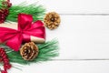 Gift box with red ribbon bow and branch christmas tree with cone on white wooden vintage background Royalty Free Stock Photo