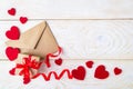 Gift box with red ribbon bow, brown paper envelope and valentine hearts on a white wood textured surface. Greeting card with copy Royalty Free Stock Photo