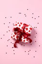 Gift box with red ribbon bow and hearts confetti on pastel pink background. Happy Valentines Day, Mothers day, birthday concept Royalty Free Stock Photo