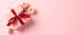 Gift box with red ribbon bow, rose flowers, confetti on pink background Royalty Free Stock Photo