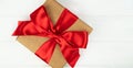 Gift box with red ribbon bow on white wooden background. Copy space. Close-up. Top view. Flatlay Royalty Free Stock Photo