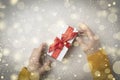 Gift box with red ribbon in female hands With golden snowflakes.