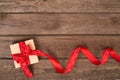 Gift box and red ribbon with tag on wood background space. Royalty Free Stock Photo