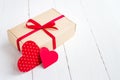 Gift box with a red ribbon  two red hearts on a white wooden background. Valentine's day background Royalty Free Stock Photo