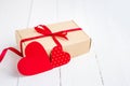 Gift box with a red ribbon  two red hearts on a white wooden background. Valentine's day background with copy space Royalty Free Stock Photo